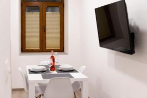 Oliver street apartment Vipava في فيبافا: طاولة بيضاء مع كراسي وتلفزيون على جدار