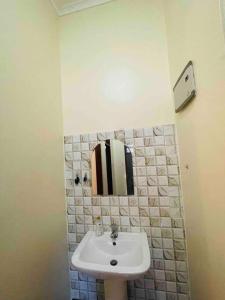 a bathroom with a sink and a mirror at 1 Bed Cozy Apartment Free Wi-Fi Netflix Hot Shower in Dar es Salaam