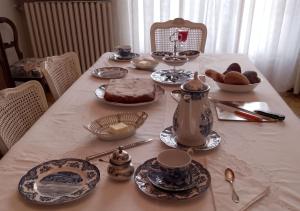 - une table avec une nappe blanche, un gâteau et de la vaisselle dans l'établissement Il Nido Segreto b&b-Villa Varinelli, à Varano Borghi
