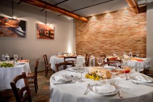 uma sala de jantar com mesas e cadeiras brancas e uma parede de tijolos em Agriturismo Ca' Brusà em Monforte dʼAlba