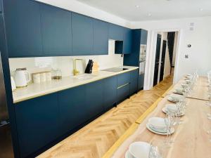 a kitchen with blue cabinets and white plates on a long table at Social Central - No 1 for large groups in Cardiff