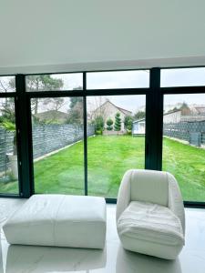 einen weißen Stuhl in einem Zimmer mit einem großen Fenster in der Unterkunft Maison lumineuse à Torcy in Torcy
