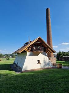a building with a chimney on top of a field at Cihelna Hříběcí in Pelhřimov