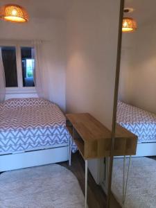 a room with two beds and a desk and a mirror at Cocooning little house in Viry-Châtillon
