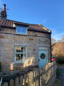 a stone house with a blue door and a fence at Hideaway Cottage in Whitby