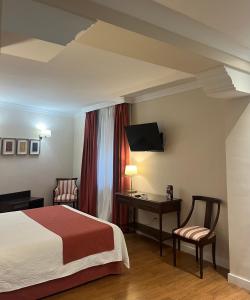 una camera d'albergo con letto, scrivania e sedia di Hotel Santo Domingo Lucena a Lucena