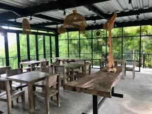 un restaurant avec des tables et des chaises en bois ainsi que des fenêtres dans l'établissement Kraras Munduk Guest House & DonBiyu Rendezvous Restaurant, à Munduk