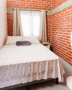 ein Schlafzimmer mit einem Bett mit Ziegelwand in der Unterkunft Entre Pinos in Comayagua