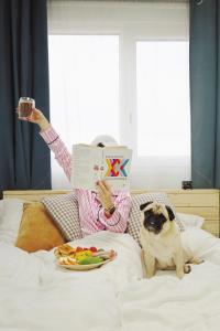 a person laying in bed reading a book with a dog at Greta Hillside in Buceş-Vulcan