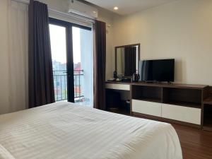1 dormitorio con 1 cama, TV y ventana en Paragon Noi bai Hotel & Pool, en Hanói
