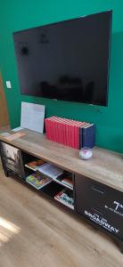 stolik z książkami i telewizor z płaskim ekranem w obiekcie Apartman HD w mieście Ðakovo