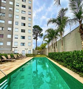 a swimming pool in front of a building with palm trees at Aconchegante Apartamento no coração de Santo Amaro in São Paulo