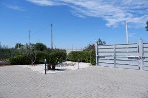 a white fence and a brick driveway with plants at Terrazza sul Plemmirio in Siracusa