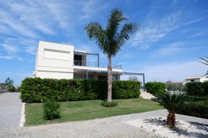 a white house with a palm tree in front of it at Terrazza sul Plemmirio in Siracusa