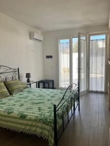 Schlafzimmer mit einem Bett mit grüner Tagesdecke und Glasschiebetüren in der Unterkunft Casa Giulia in Marina di Leuca