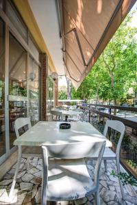 an outdoor patio with tables and chairs and windows at Hotel Tiziana in Rimini