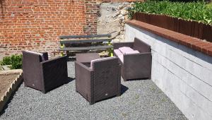 drie rieten stoelen en een bank naast een stenen muur bij Maison de ville in Pont-Audemer