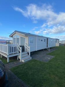 a white mobile home with a porch and a bench at Orchid meadows retreat in Ashington