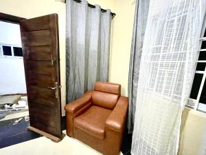 a brown chair sitting in a room with curtains at Accra Luxury Apartments At The Sanga Estates in Accra