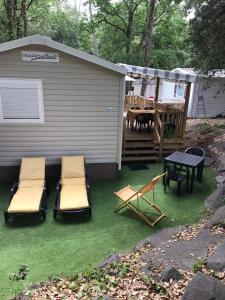 un patio trasero con sillas, una mesa y una casa en Mobil home tout confort 3 chambres camping Les Pierres Couchées, en Saint-Brevin-les-Pins