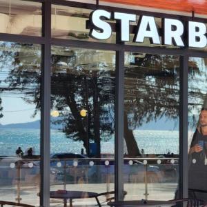 Een man die voor een Starbucks raam staat. bij The Title V Condos by Gregory in Rawai Beach