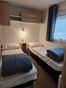 two beds in a small room with a window at Mobil home tout confort 3 chambres camping Les Pierres Couchées in Saint-Brevin-les-Pins