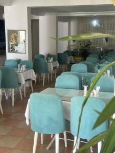 a dining room with blue chairs and tables at Deniz Hotel in Finike