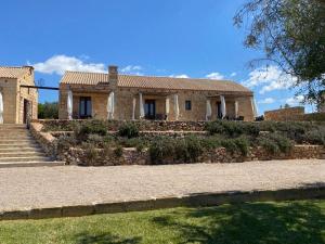 a house with a stone wall and a yard at Masseria Cisternella in Alliste