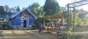 eine Gruppe von Menschen, die vor einem blauen Haus stehen in der Unterkunft Megitar moonstar Homestay in Bijanbāri Bāzār