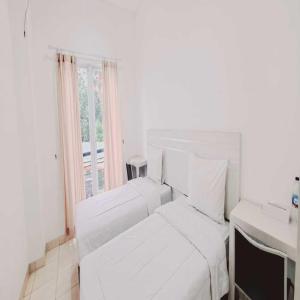 a white bedroom with a bed and a window at Tos Residence in Tangerang