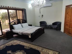 a bedroom with a bed and two chairs and a chandelier at Askari Gold Crest in Peshawar