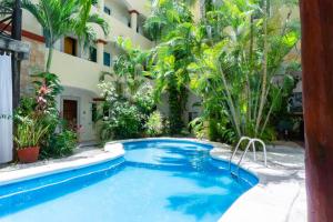 a swimming pool in front of a building with palm trees at Magic Paradise by BVR in Playa del Carmen