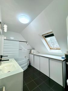 ein weißes Bad mit einem Waschbecken und einem Fenster in der Unterkunft Maison lumineuse à Torcy in Torcy