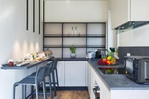a kitchen with white cabinets and a counter with chairs at Villa "LE GILDA" 5 STELLE in Massa