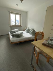 Schlafzimmer mit einem Bett, einem Tisch und einem Fenster in der Unterkunft Swiss Alpine Hideaway in Sedrun