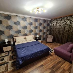 Un dormitorio con una cama azul y un sofá púrpura en Квартира посуточно в центре г.Петропавловска en Petropavlovsk