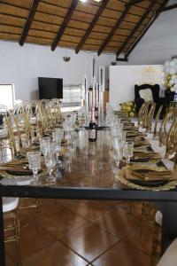 un lungo tavolo con bicchieri e una bottiglia di vino di Makhadzi's clouds lodge a Dalmada