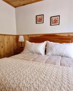 Cabañas Millalauquen في بوكون: غرفة نوم بسرير كبير ومخدات بيضاء