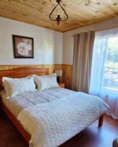 1 dormitorio con cama y ventana en Cabañas Millalauquen, en Pucón
