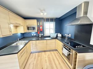 a kitchen with black counter tops and wooden cabinets at Casa Crusoe - Part of the The Bay Filey Holiday Village with pool, gym and direct beach access, pub, restaurant, tennis and meadows walks in Reighton +38 photos