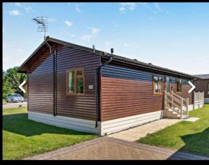 a small wooden building with a porch on a lawn at Ness Lodge in Little Habton