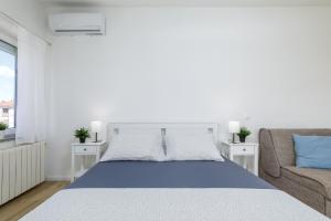 a white bedroom with a bed and a couch at Sea La Vie in Fažana