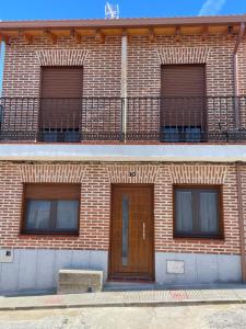 um edifício de tijolos com uma porta e uma varanda em Casa Capricho em Horcajo de las Torres