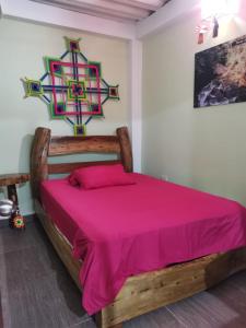 a bedroom with a wooden bed with a pink bedspread at POSADA KAUAI in Mocoa