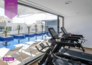 a gym with three treadmills and a swimming pool at JourneyJoy I Luxury Apartment with Pool & Gym in Al Karm