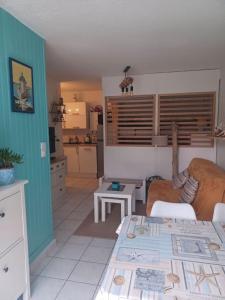 sala de estar con sofá y cocina en AGREABLE REZ DE JARDIN AVEC TERRASSE PROCHE PLAGE, en Saint-Georges-de-Didonne