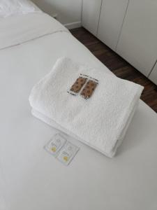 a white blanket on a bed with two controllers on it at Cocon familial proche de Paris in Issy-les-Moulineaux