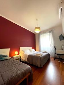 a bedroom with two beds and a red wall at Lucens Domus Appartamento Roma quartiere Trieste - vicino Metro b1 - in Rome