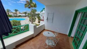 balcón con mesa, sillas y vistas a la piscina en Precioso apartamento en Playa Bastián en Costa Teguise