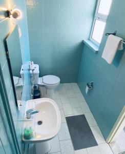 Baño azul con lavabo y aseo en Central Atlantic Beach Guesthouse, en Costa da Caparica